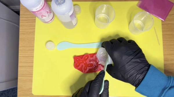 Top down view of hands pouring resin into a silicone mould