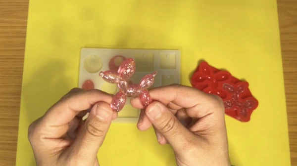 Hands holding glittery pink balloon dog made out of resin