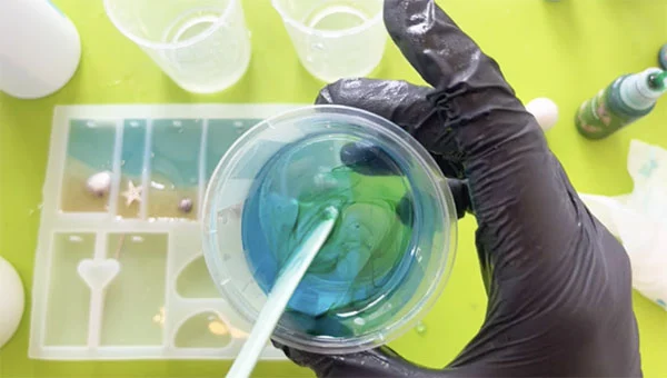 Green colourant being mixed into a cup with blue resin