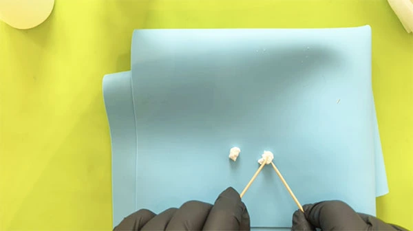 Toothpicks being used to form white clay into cloud shapes