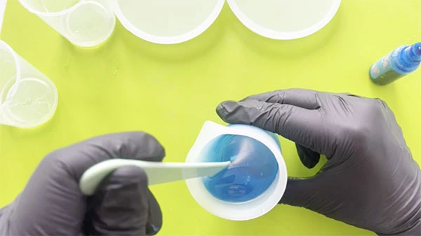 Gloved hands mixing blue resin