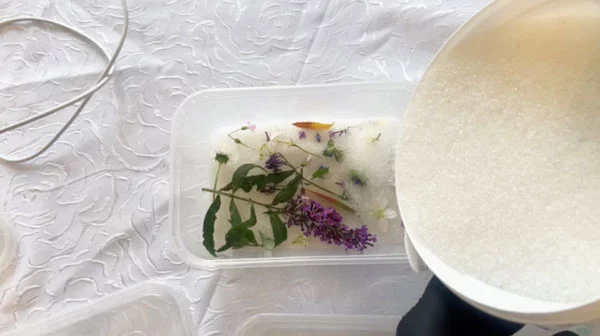 Silica gel being poured into a container full of flowers