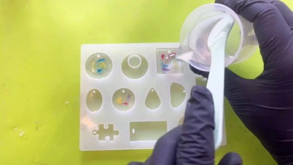 Clear resin being poured on top of patterned resin in moulds