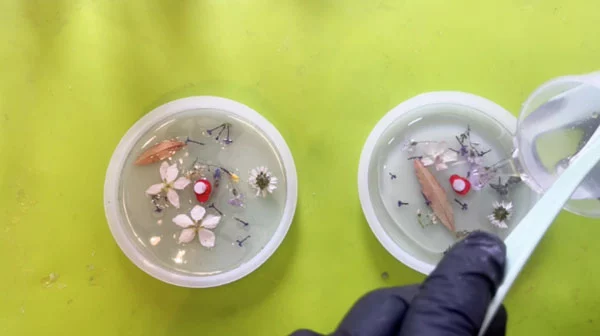 Clear resin being poured over resin with embedded flowers